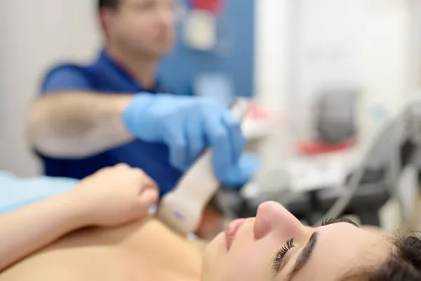 ONCOLOGO EXAMINANDO LAS MAMAS Y LOS GANGLIOS LINFATICOS MEDIANTE ECOGRAFIA