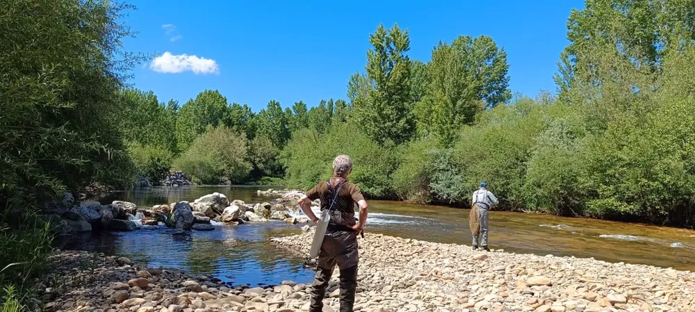 Dos hombres pescan a la orilla de un río. - JCYL